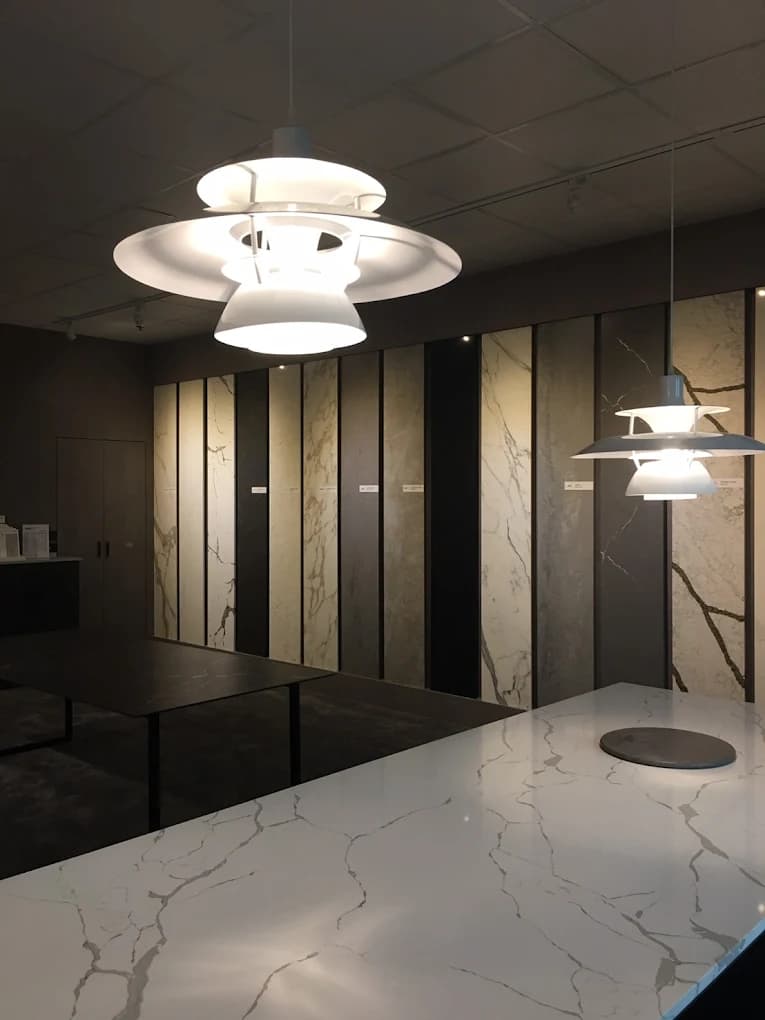 Interior display of large marble and stone slabs in a showroom, with modern ceiling lights and a marble countertop.